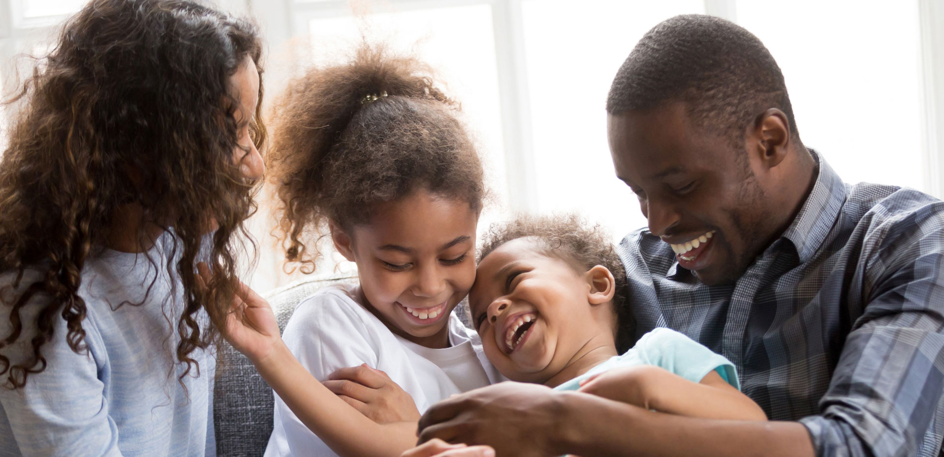African American family of four smiling and sitting on couch
