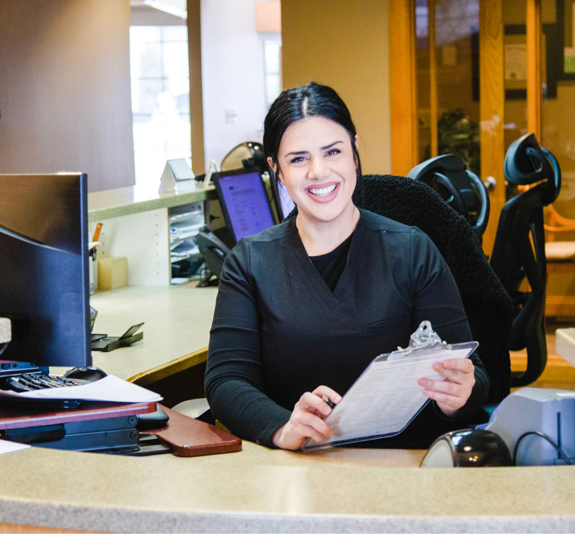 marisela sitting at front desk and smiling at camera