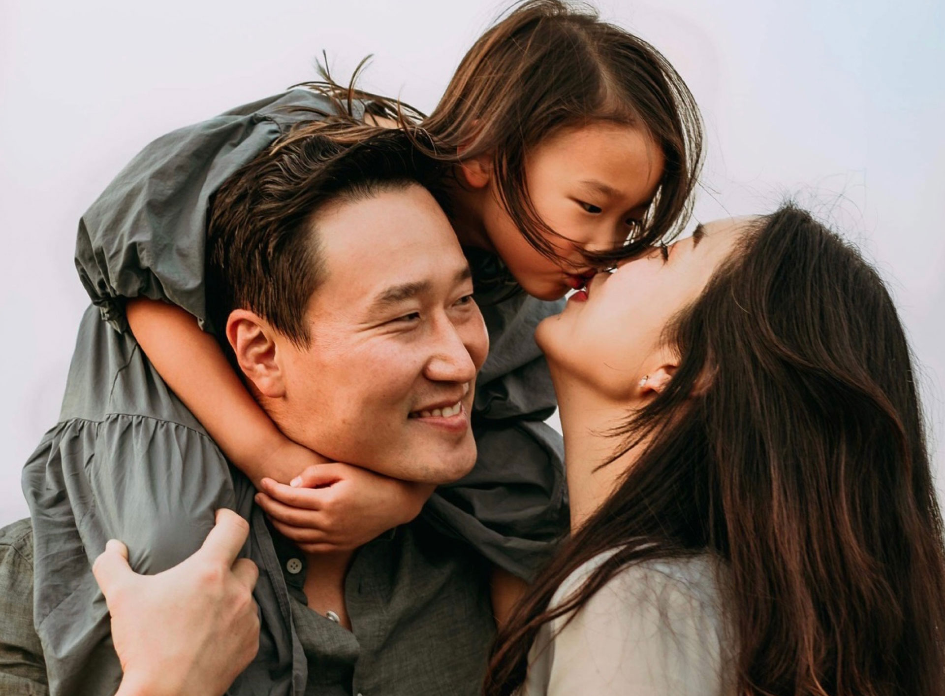 Dr. Sim smiling with wife and young daughter